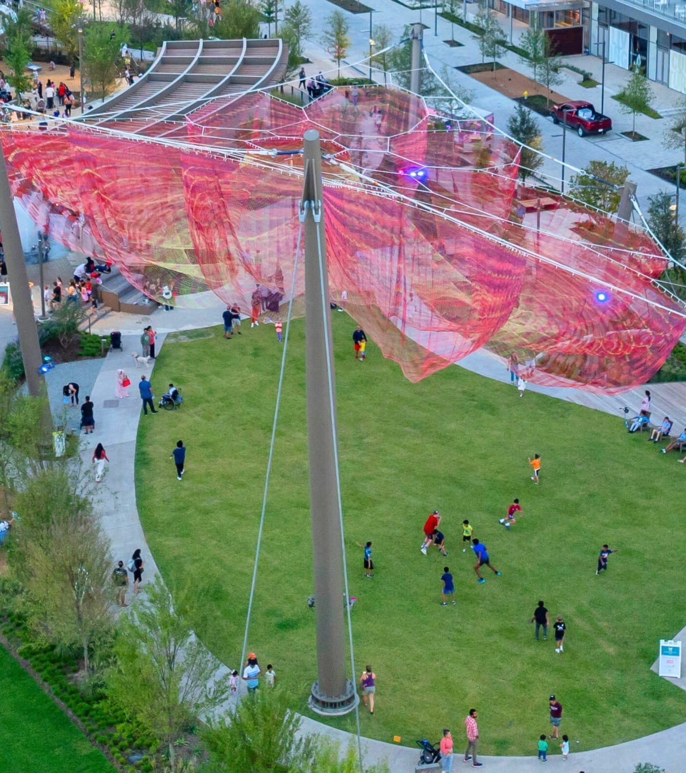 Aerial view of families on the Arts Plaza lawn under the Butterfly Rest Stop sculpture